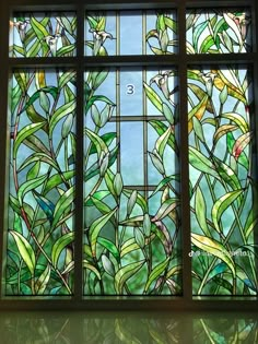 a stained glass window with green plants in it