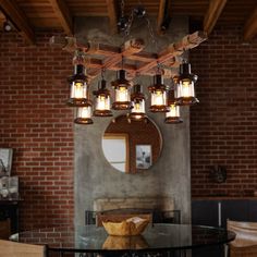 a chandelier hanging over a glass table in a room with exposed brick walls