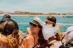 three people sitting on a boat in the water wearing hats and sun visors