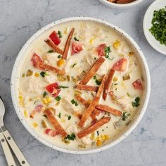 a bowl filled with soup next to two bowls full of vegetables and other food items