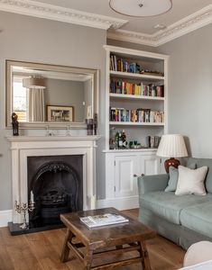 a living room with a couch, coffee table and bookcases in front of a fireplace