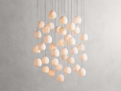 a chandelier made out of white eggs hanging from strings on a gray wall