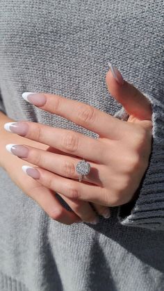 a woman's hands with white and silver manicures holding an engagement ring