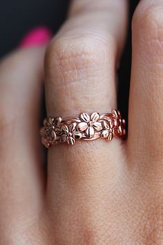 a close up of a person's hand wearing a ring with flowers on it