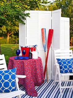 an outdoor patio with chairs and a table covered in blue and white pillows, umbrellas and other items