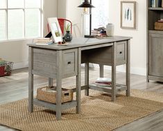 a wooden desk sitting on top of a rug next to a book shelf filled with books