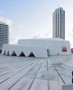 a person sitting on a bench in front of a building with two tall buildings behind it