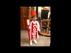 a young boy dressed up as a candy bar holding a red and white sign with the word cola on it