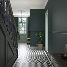 a hallway with green walls and black and white tile flooring next to a plant