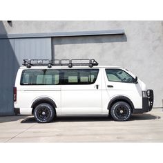 a white van parked in front of a building with a roof rack on the top