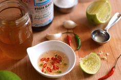 there is a bowl of soup on the table with limes and other ingredients around it