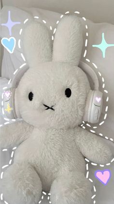 a white stuffed animal with headphones on it's ears sitting in a bed