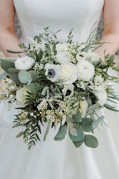 a bridal holding a bouquet of white flowers and greenery