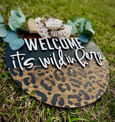 a wooden sign that says, welcome it's wild in love on the grass