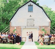 a bride and groom standing at the end of their wedding ceremony in front of an old barn