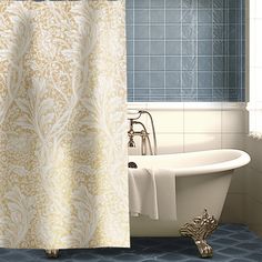 a bath tub sitting next to a shower curtain in a bathroom with blue tiles on the walls