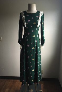 "1970s handmade prairie dress cotton w/lace trim zip up back ties below bust front to back long sleeve w/elastic wrist cuff dark green w/multi-color floral pattern very good vintage condition, light wear no size label tag (measures like xs/s but please go by measurements) measures, lying flat, shoulder-14 1/2\" bust-16 1/2\" waist-14\" hip-22 1/2\" sleeve-23\" length-51\"" Green Lace Trim Dress For Fall, Vintage Long Sleeve Green Dress, Fitted Cottagecore Dress For Fall, Green Long Sleeve Cottagecore Dress, Fitted Long Sleeve Dress With Vintage Print, Vintage Floral Print Winter Dress, 1970s Green Long Sleeve Dress, 1970s Style Green Long Sleeve Dress, Long Sleeve Dresses For Vintage Fashion In Spring