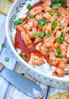 a bowl filled with shrimp and sauce next to crackers