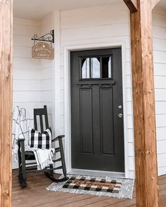 a porch with rocking chairs and a black door