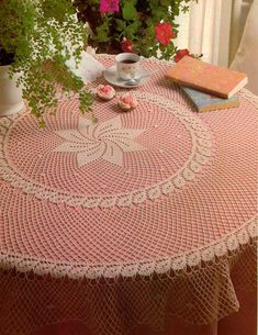 a table topped with pink crocheted doily next to a potted plant