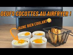 four small containers filled with food sitting on top of a wooden table next to an air fryer