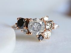 an engagement ring with black and white stones on it's side, sitting on a table