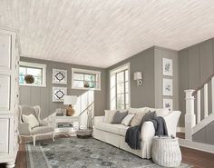 a living room with gray walls and white furniture on the floor, along with an area rug