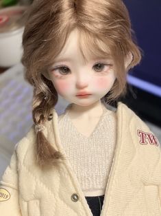 a close up of a doll wearing a sweater