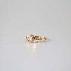 This unique Evil Eye ring features a round opal stone surrounded by a halo of clear cubic zirconia stones, all set on a gold plated band. The opal stone at the center of the ring glows with a soft iridescent light, adding a touch of magic to the overall design. The ring is delicate and dainty, yet eye-catching due to its unique shape and design. It would make a great gift for someone who loves opals or unique jewelry pieces. 10k gold plated sterling silver base Adjustable US size 6-8 Jewelry car Gold Round Cut Opal Ring, Gold Opal Ring With Halo, Gold Opal Ring With Diamond Accents, Gold Opal Ring With Halo Setting, Gold Opal Ring With Halo Design, Gold Opal Crystal Promise Ring, Gold Opal Diamond Halo Ring, Gold Opal Ring With Halo Design In 14k Gold, Gold Opal Ring With Center Stone In Round Cut