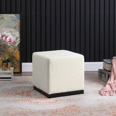 a white ottoman sitting on top of a rug in a living room next to a painting