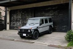 a mercedes g - class parked in front of a garage