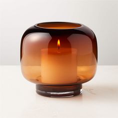 a candle that is inside of a glass vase on a table with a white background