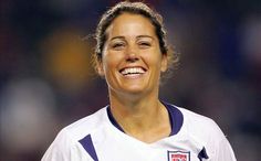 a black and white photo of a female soccer player smiling at the camera with her mouth open