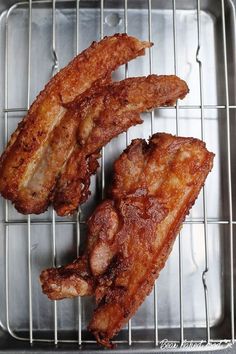 two pieces of fried meat sitting on top of a metal grill grate next to each other