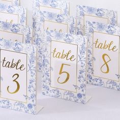 blue and white place cards with gold foil numbers on them, sitting side by side