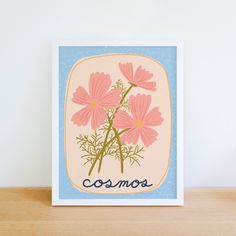 a card with pink flowers on it sitting on top of a wooden table next to a white wall