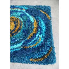 a blue area rug with yellow and blue swirls on the center, in front of a white floor