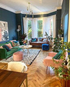 a living room filled with furniture and lots of green plants on top of a hard wood floor