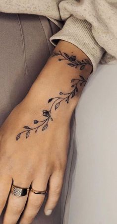 a woman's hand with a flower tattoo on her left arm and the wrist