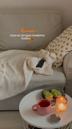 a white couch sitting next to a table with two cups and candles on top of it