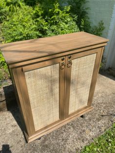 an old wooden cabinet with wicker doors on the front and sides, sitting outside