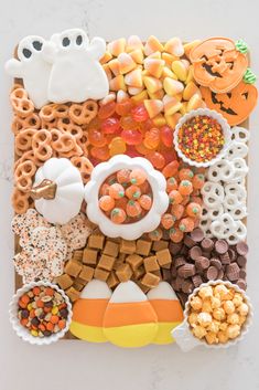 an assortment of halloween treats arranged on a white surface with candy and candies in the middle