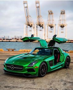 a green sports car parked in front of a body of water with its doors open