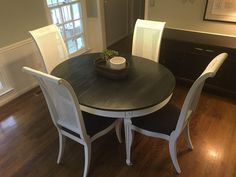 a dining room table with four chairs and a bowl on top of it, in front of a window