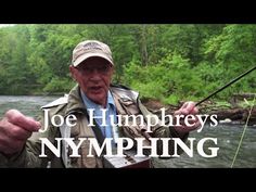 a man holding a fishing rod while standing in front of a river with the words joe humphry's nymphing on it