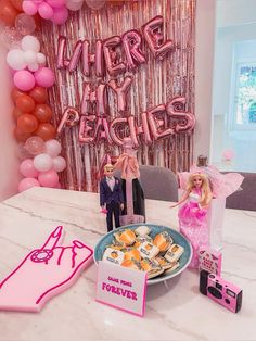 the table is set up for a barbie birthday party with pink balloons and decorations on it