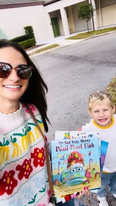 a woman holding a book next to a little boy