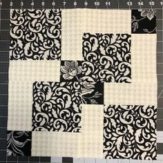 a piece of black and white quilted material on top of a cutting board next to a ruler