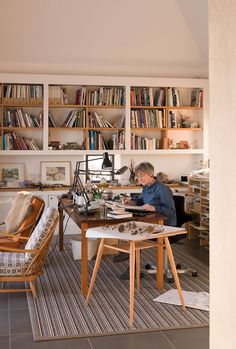 a man sitting at a table in front of a bookshelf filled with books