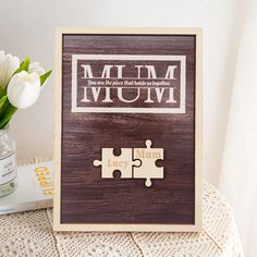 a wooden frame with the word mum on it and two pieces of puzzle next to it